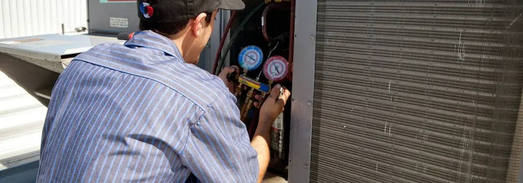 HVAC technician servicing a condenser unit in Manheim